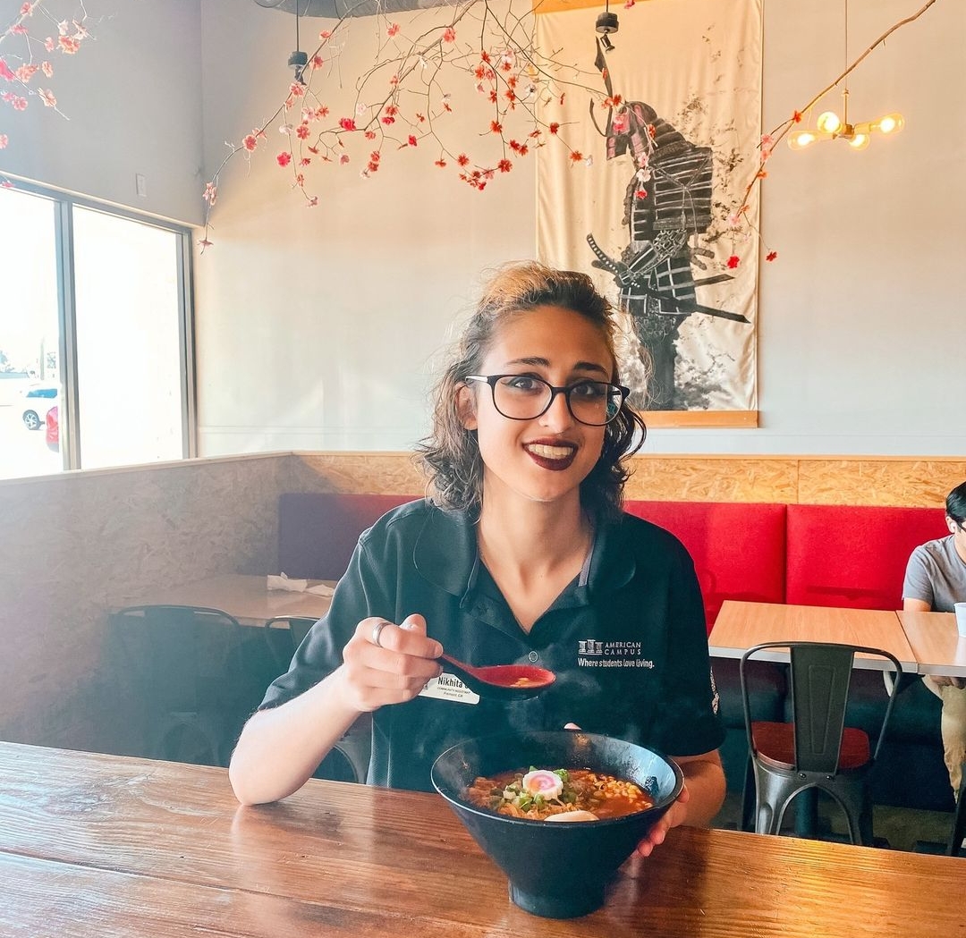 person sitting at a table in a resturant with a bowl of ramen